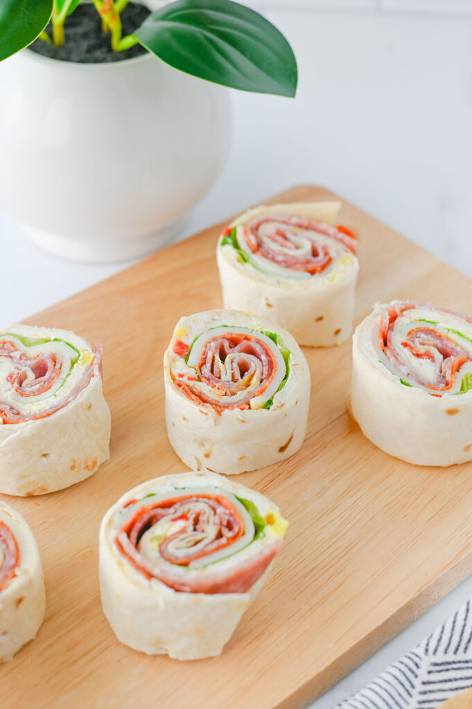 A picture of sliced italian pinwheel sandwiches with a potted plant in the background.