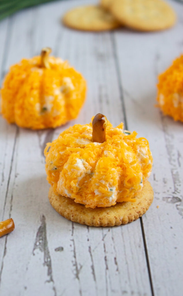 A close up picture of a pumpkin cheese ball on a Ritz cracker.