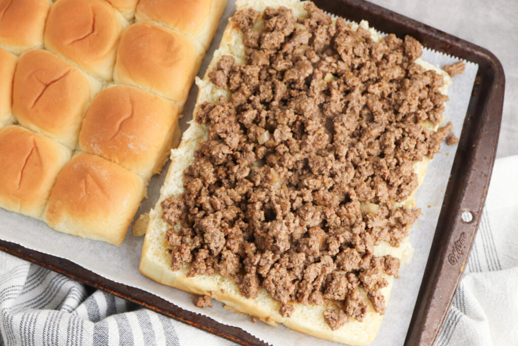 A picture of seasoned ground beef spread across Hawaiian rolls cut in half to make sandwiches.