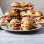 A picture of a platter of reuben sliders stacked on top of one another.