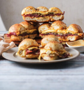 A picture of a platter of reuben sliders stacked on top of one another.