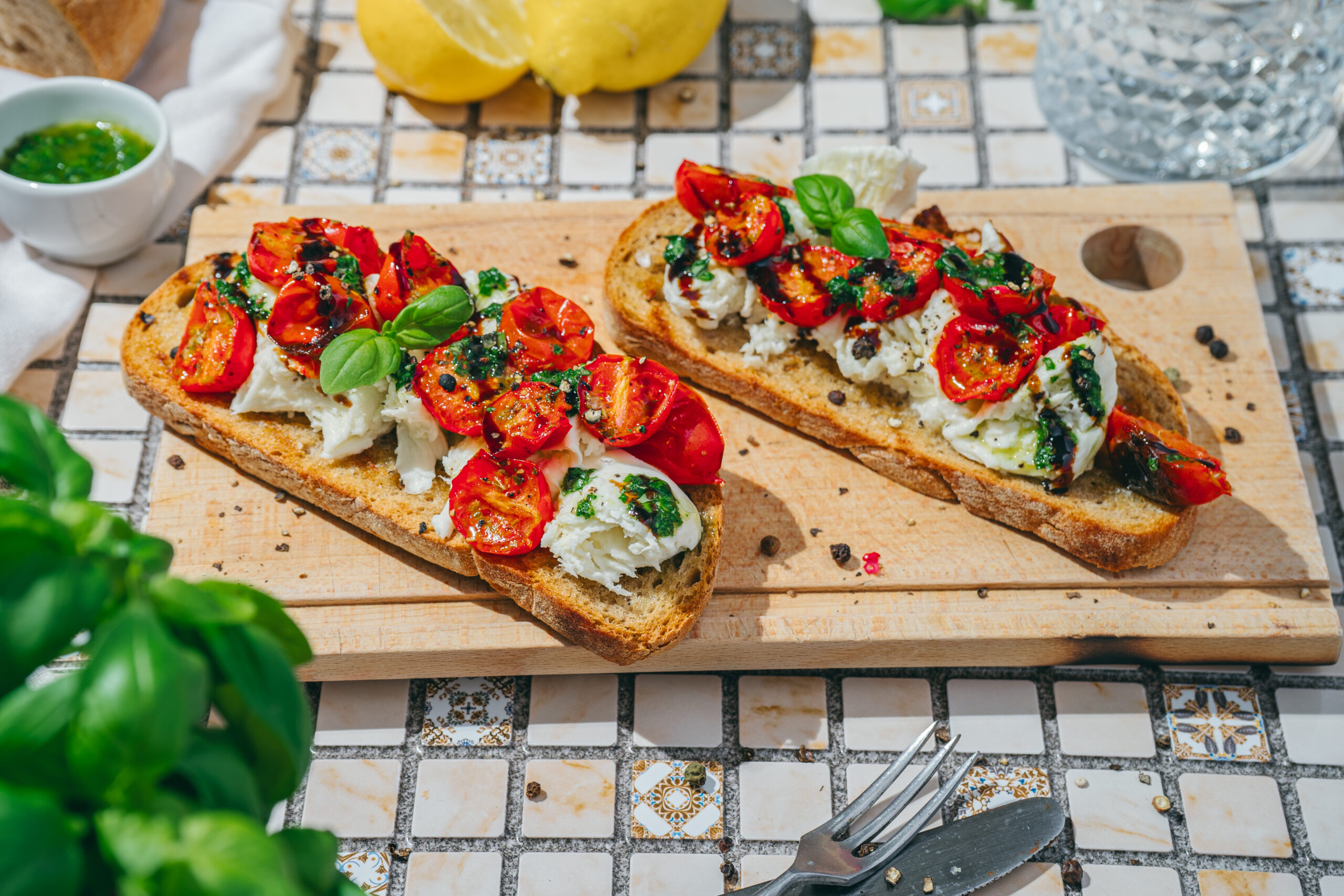 A picture of two pieces of burrata toast on a wooden serving platter.