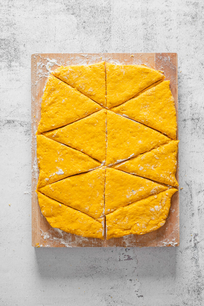 A picture of flattened pumpkin spice scone dough cut into twelve wedges.