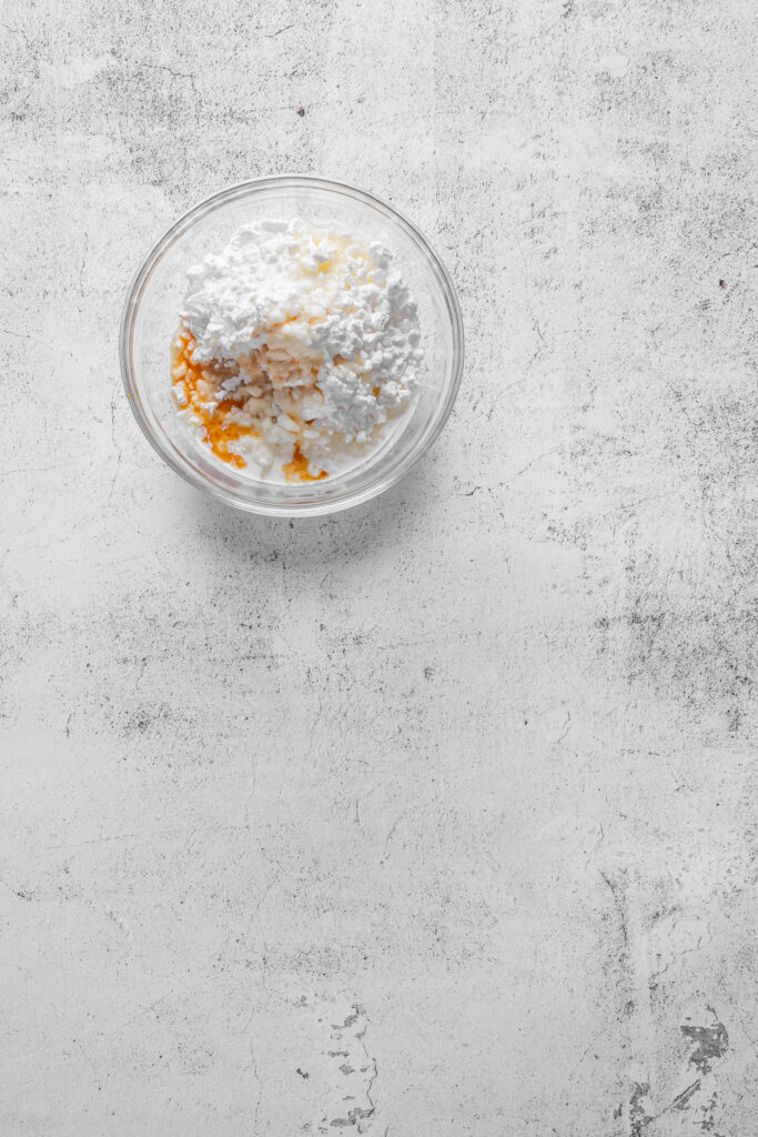 A picture of confectioner's sugar, cream, and vanilla extract unmixed in a bowl.