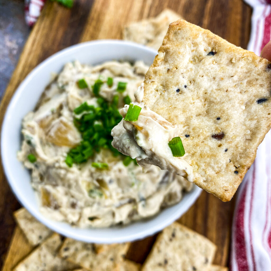 A picture of a cracker after being dipped into caramelized onion dip.