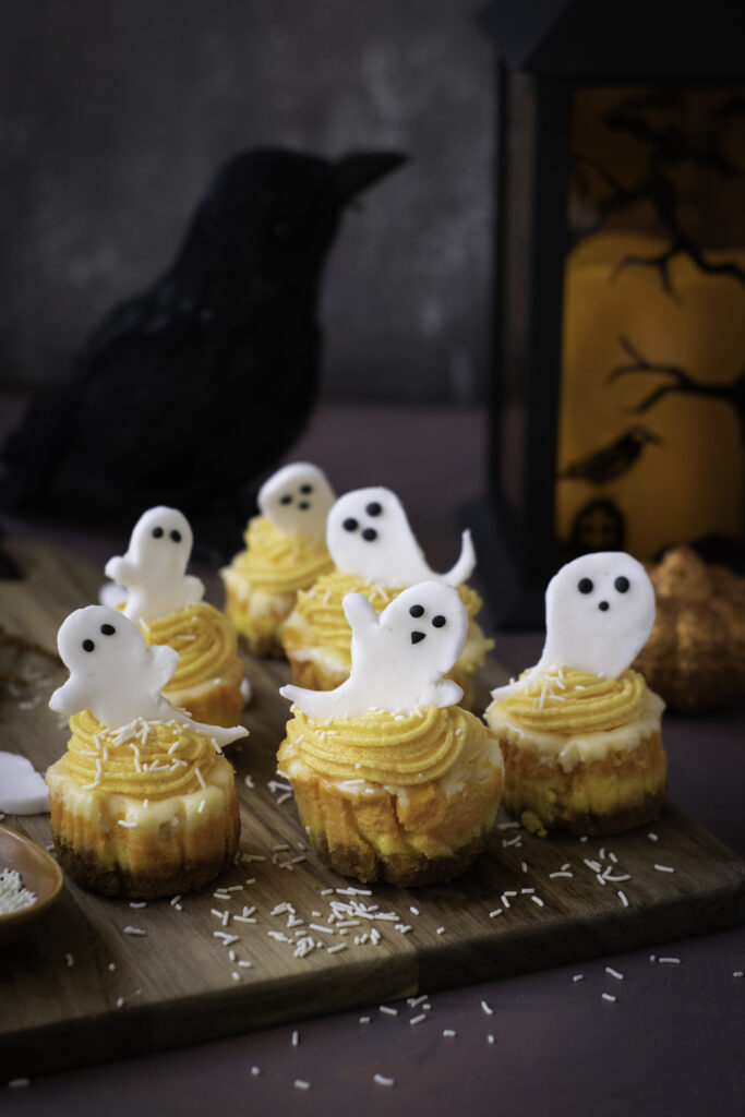A picture of halloween mini cheesecakes on a wooden serving platter.
