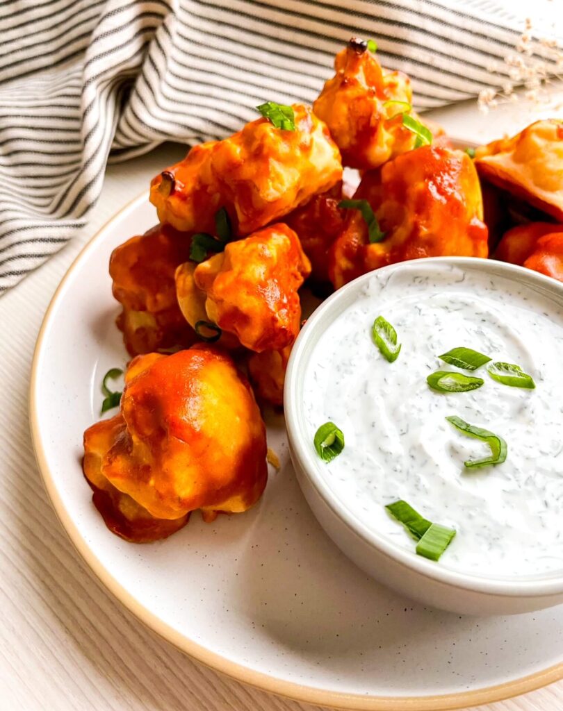 A picture of cauliflower wings on a dish with ranch in a bowl.