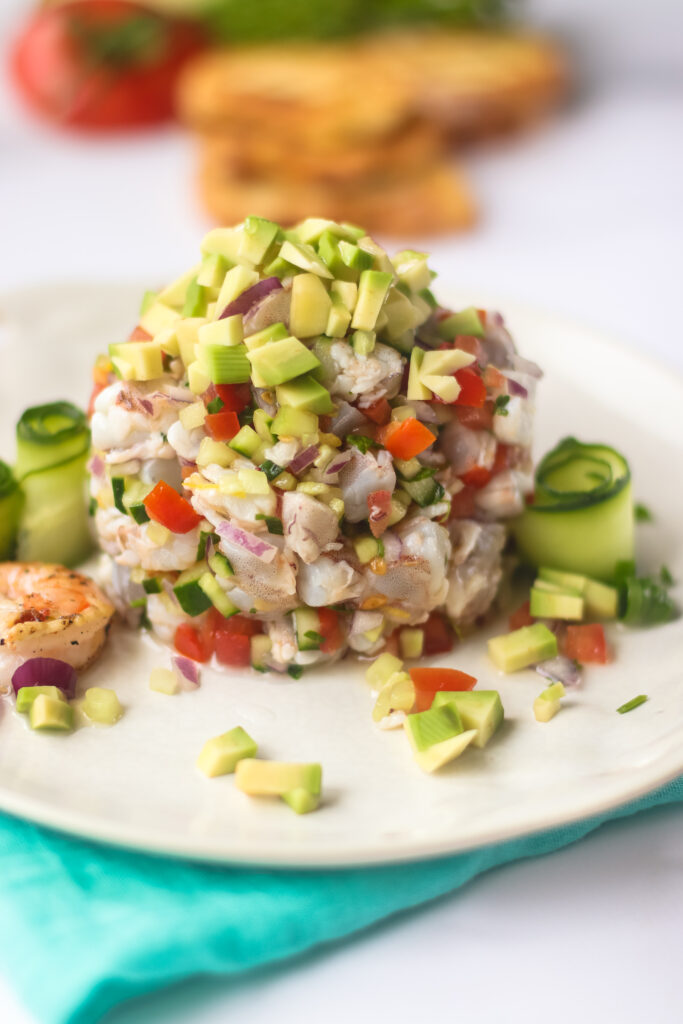 A close up picture of a serving of shrimp ceviche on a white plate.