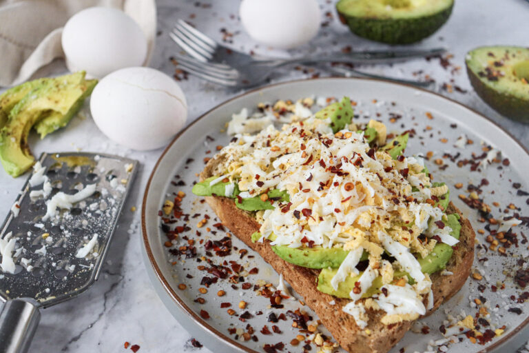 A picture of avocado toast topped with egg and spices.