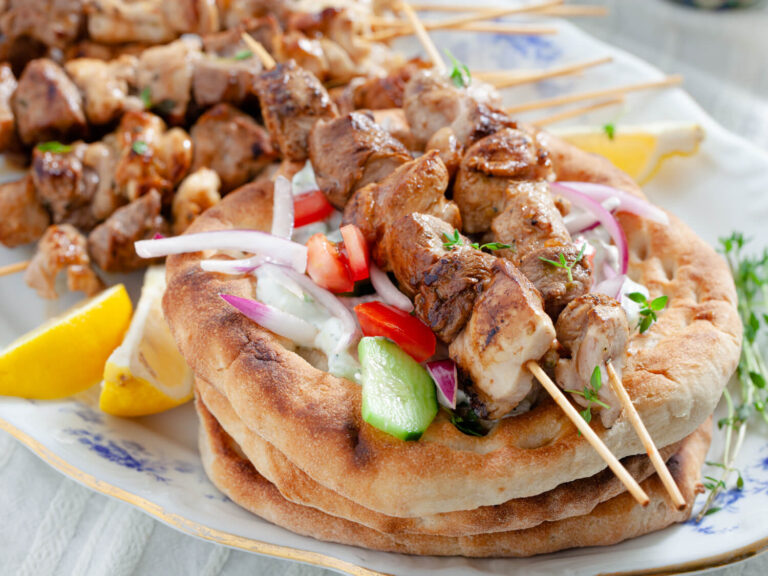 A picture of tzatziki skewers on a bed of pita bread.