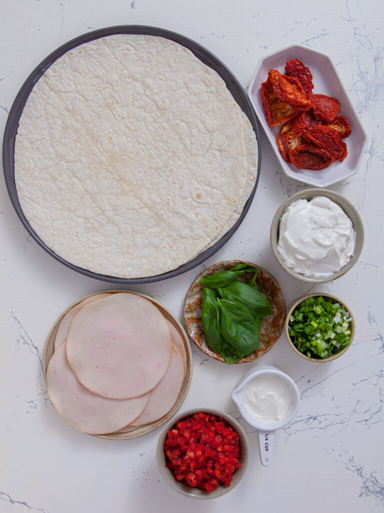 A picture of ingredients needed to make turkey tomato pinwheel sandwiches.