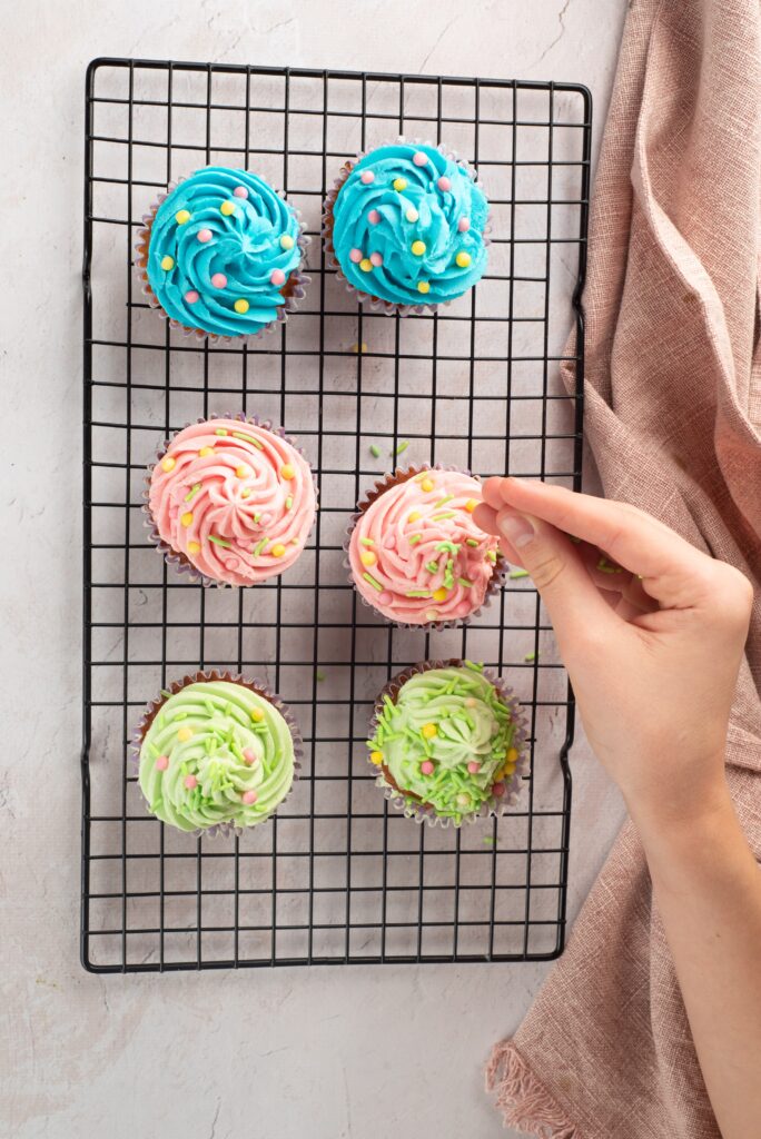 adding sprinkles to easter cupcakes