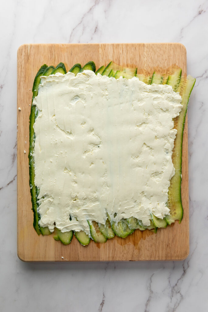 cream cheese spread out over cucumbers