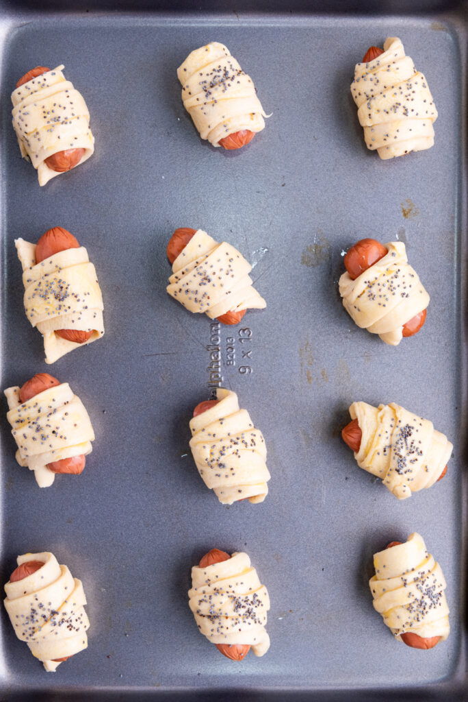 piggies in a blanket placed on a baking sheet before going into the oven