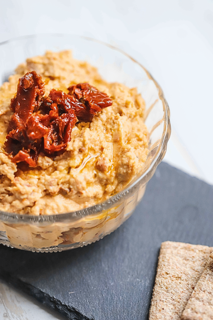 sundried tomato hummus in a bowl with crackers